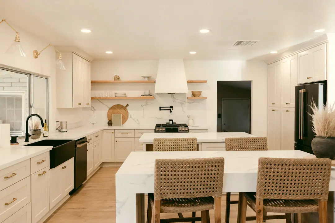 Cocina blanca con isla y taburetes de fibra